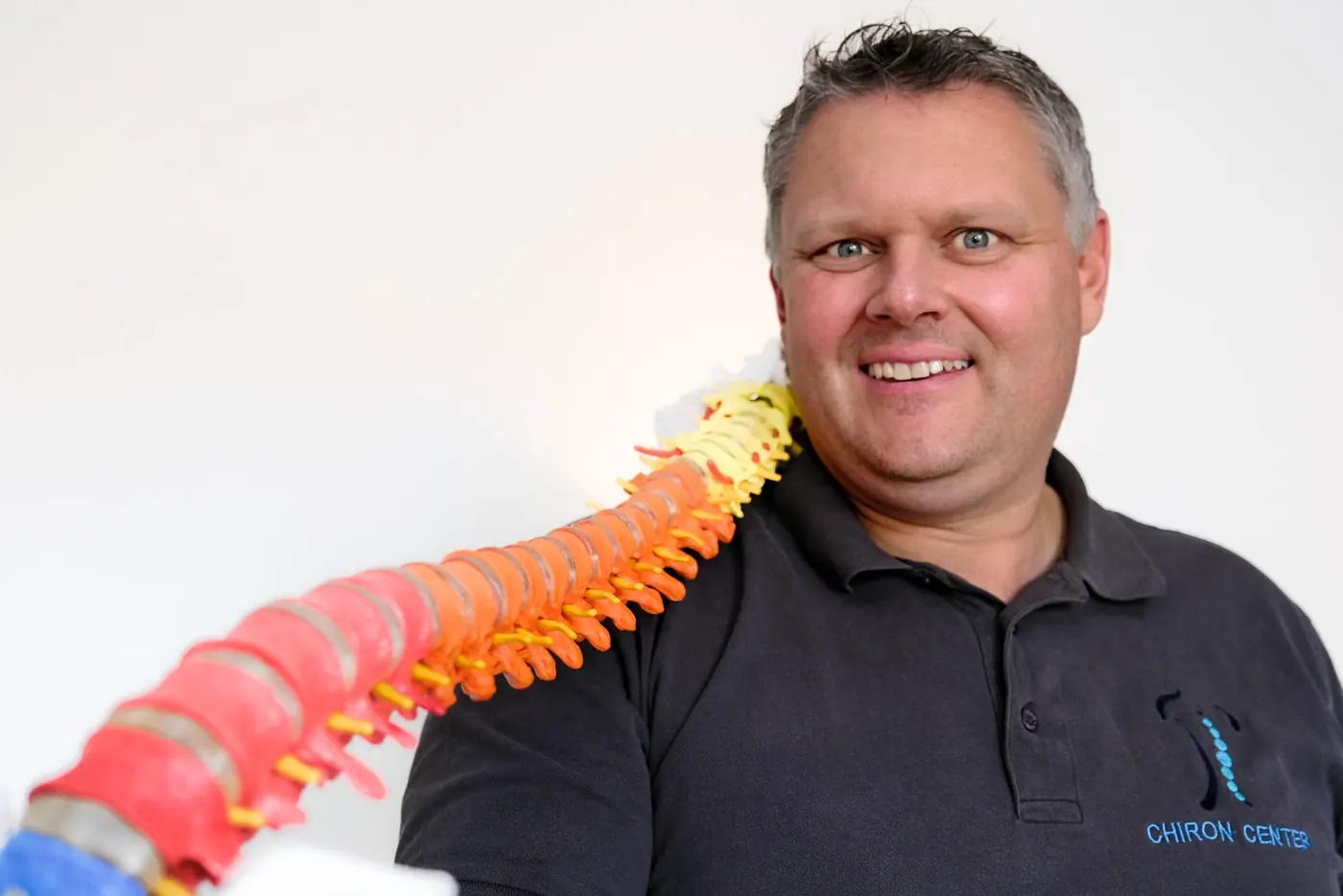 Faszientherapeut Patrick Nehmzow erklärt an einem Wirbelsäulenmodell die Verdrehung der Wirbelsäule bei Skoliose